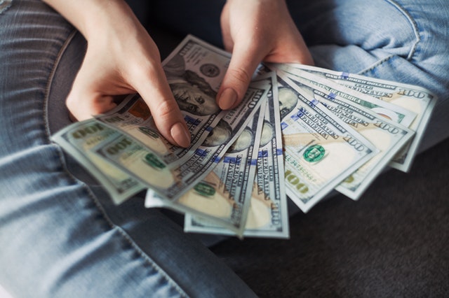 a-person-holding-several-hundred-dollars-in-us-currency