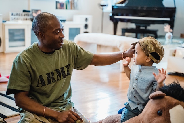pexels-george-pak-7983845 a person in an army shirt playing with a young child